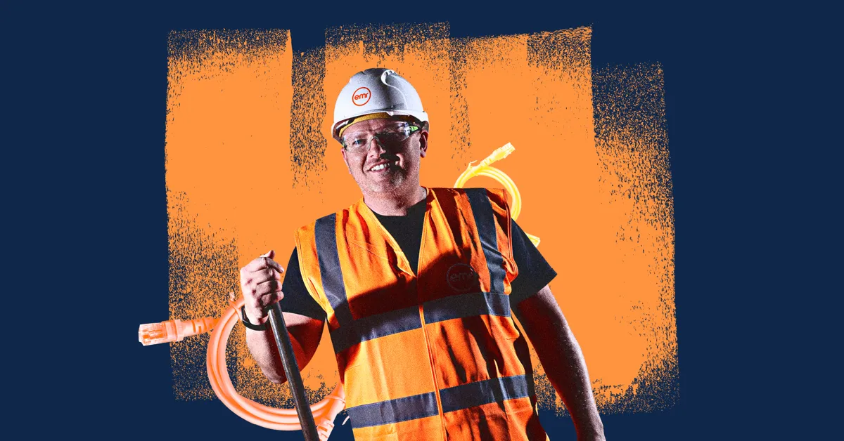 A person in a hard hat and safety vest holding a cable.