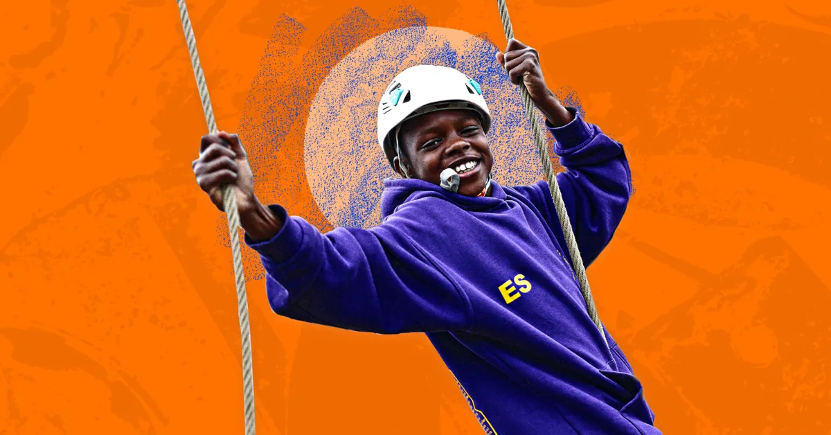 A child wearing a helmet and a purple hoodie zip-lining against an orange background.