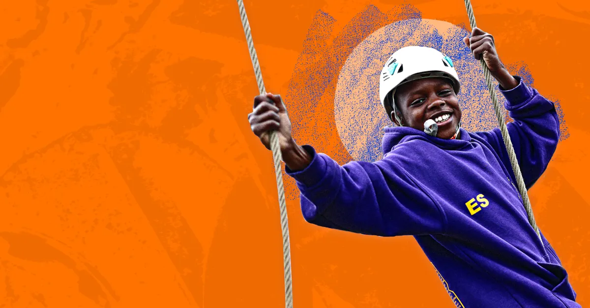 A child wearing a helmet and a purple hoodie zip-lining against an orange background.