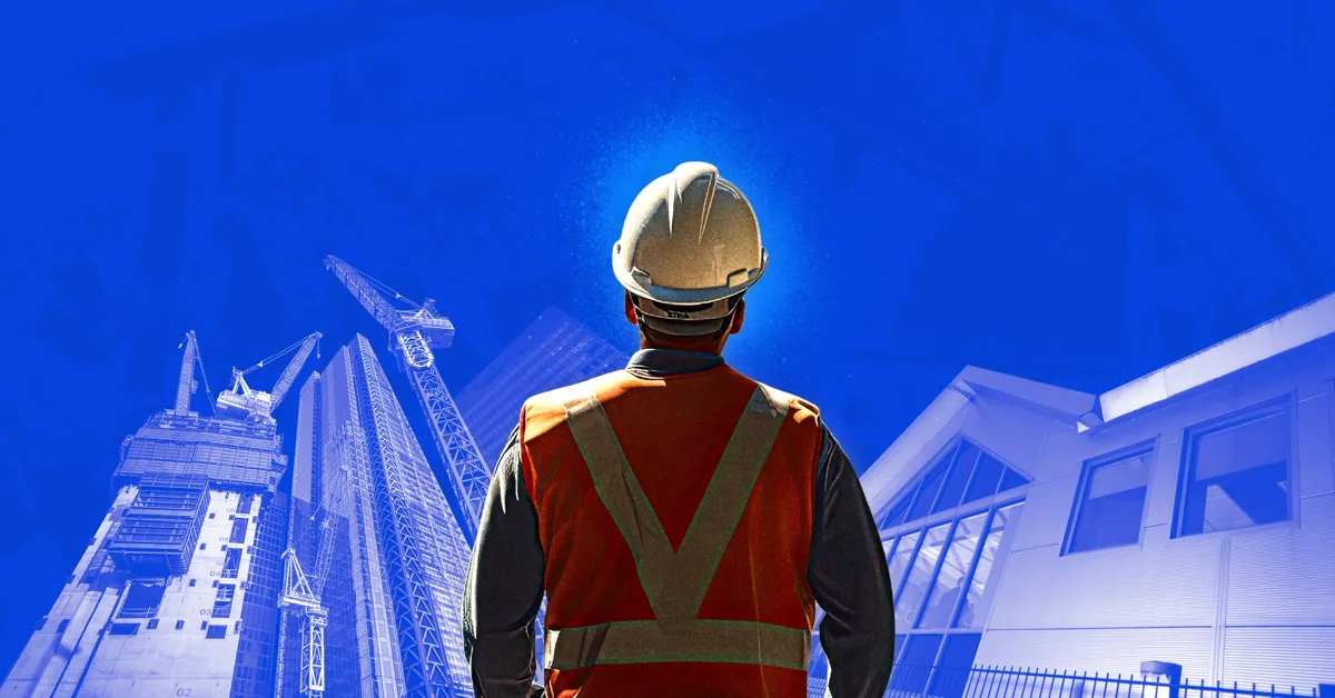 A person in a hard hat and safety vest looking at buildings under construction.