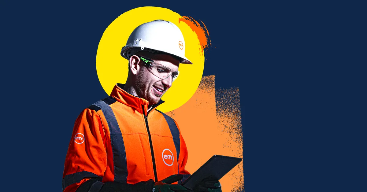 A person in a hard hat and safety vest holding a tablet.