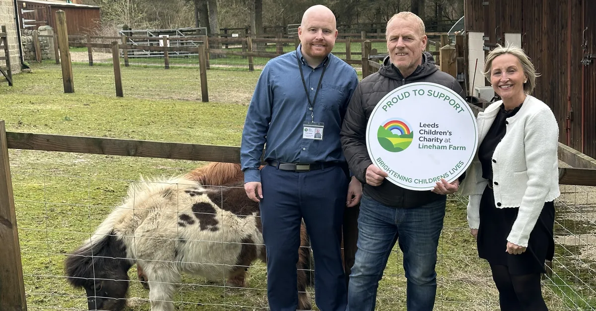 Three people standing next to a fence and a pony holding a sign.