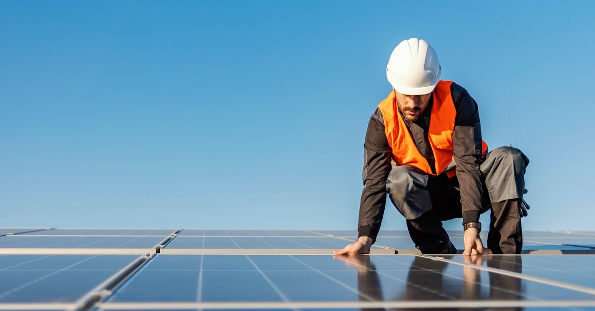 Person inspecting solar panels on a roof