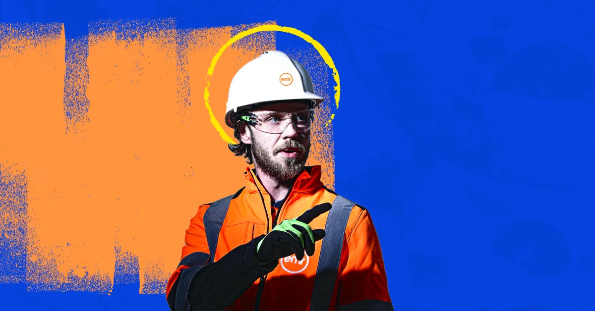 A person wearing a hard hat and safety glasses stands in front of a blue and orange background.