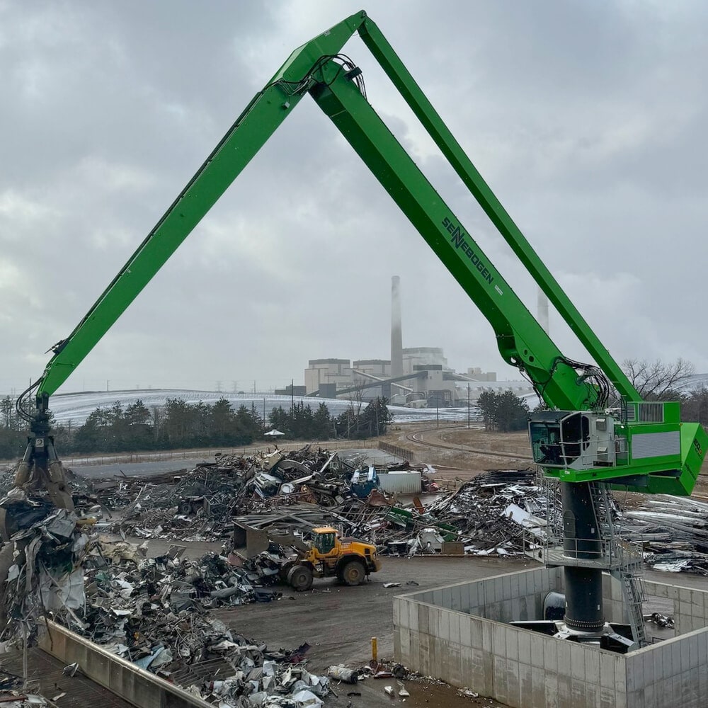 Grabber with a metal in its claws standing in a recycling facility