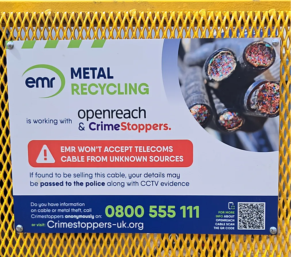 A sign with a yellow border and a picture of cables. The text reads EMR is working with Openreach and CrimeStoppers.