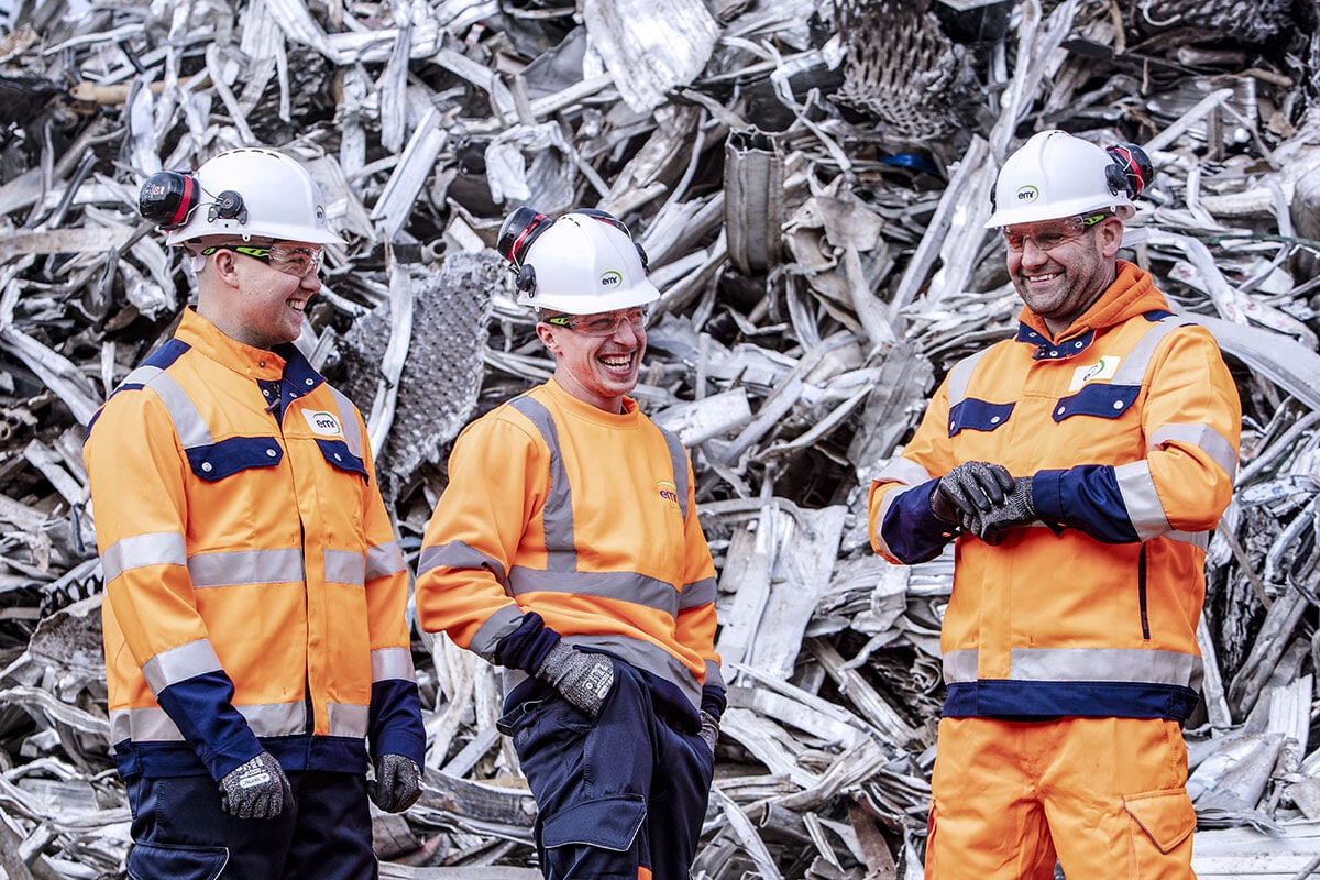 People stood in front of a pile of metal.