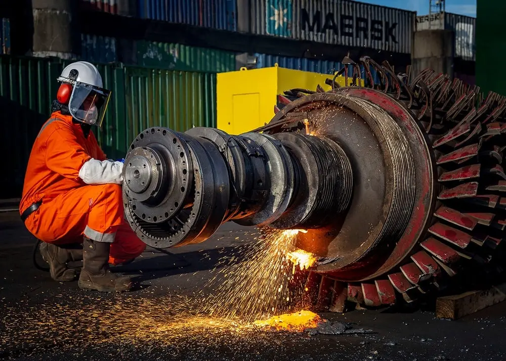 Person bending down and welding a piece of metal.