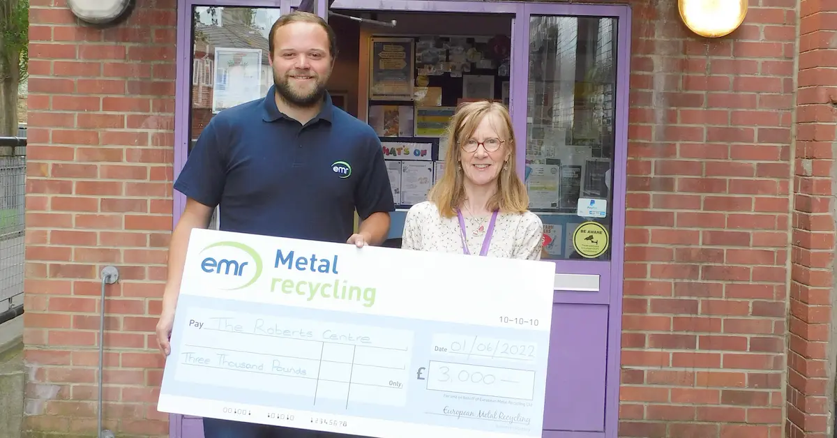 Two people stood outside EMR Portsmouth holding a novelty-sized cheque