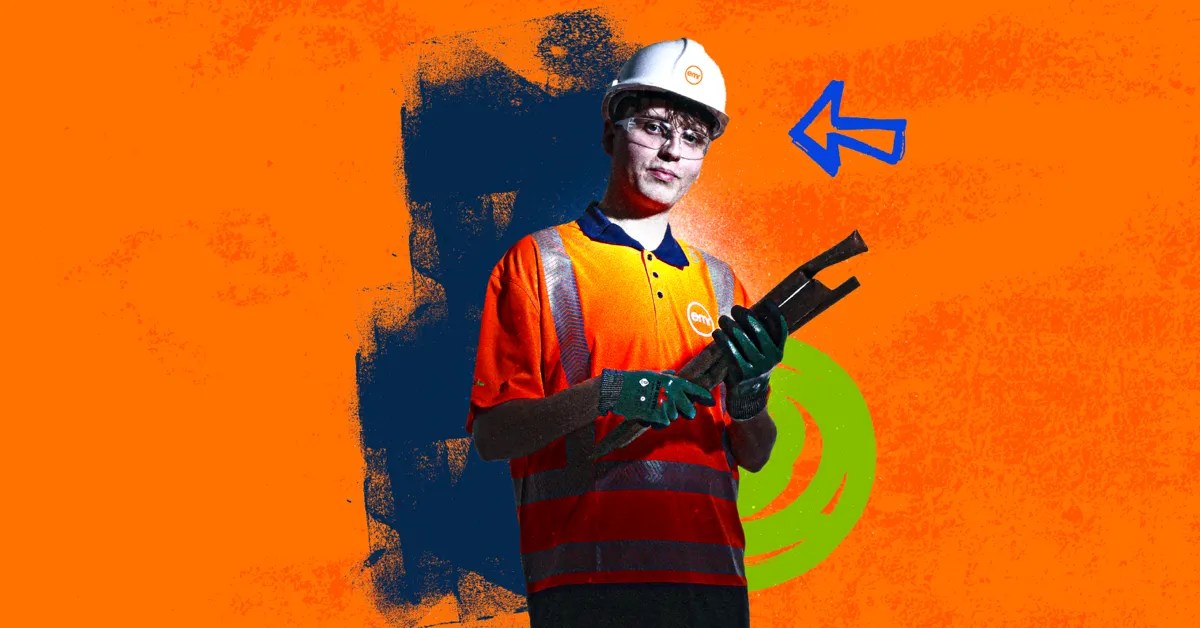 A person in a hard hat and safety vest holding a black tool against an orange background.