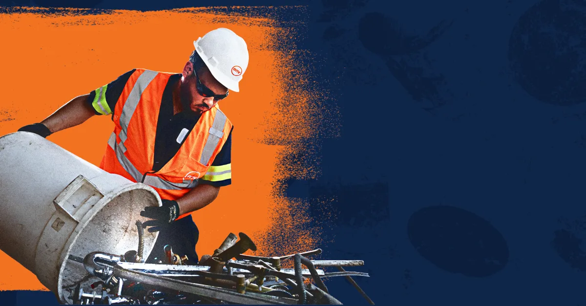 A person wearing a hard hat and safety vest working on a pipe.