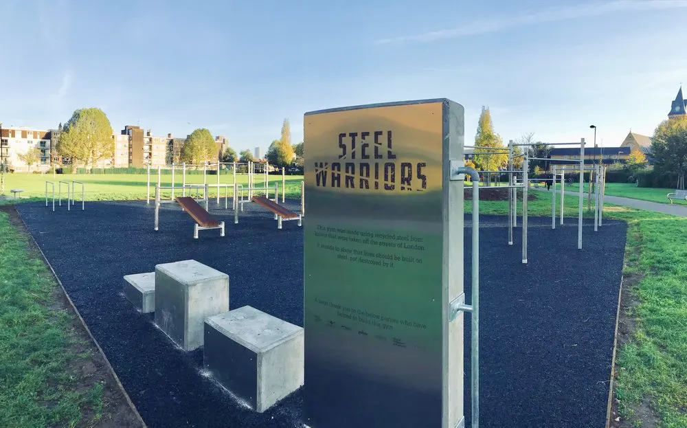 Gym equipment in a park with signage saying 'Steel Warriors'