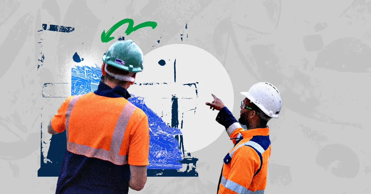 Two construction workers in hard hats and high-visibility vests discussing a pile of materials.