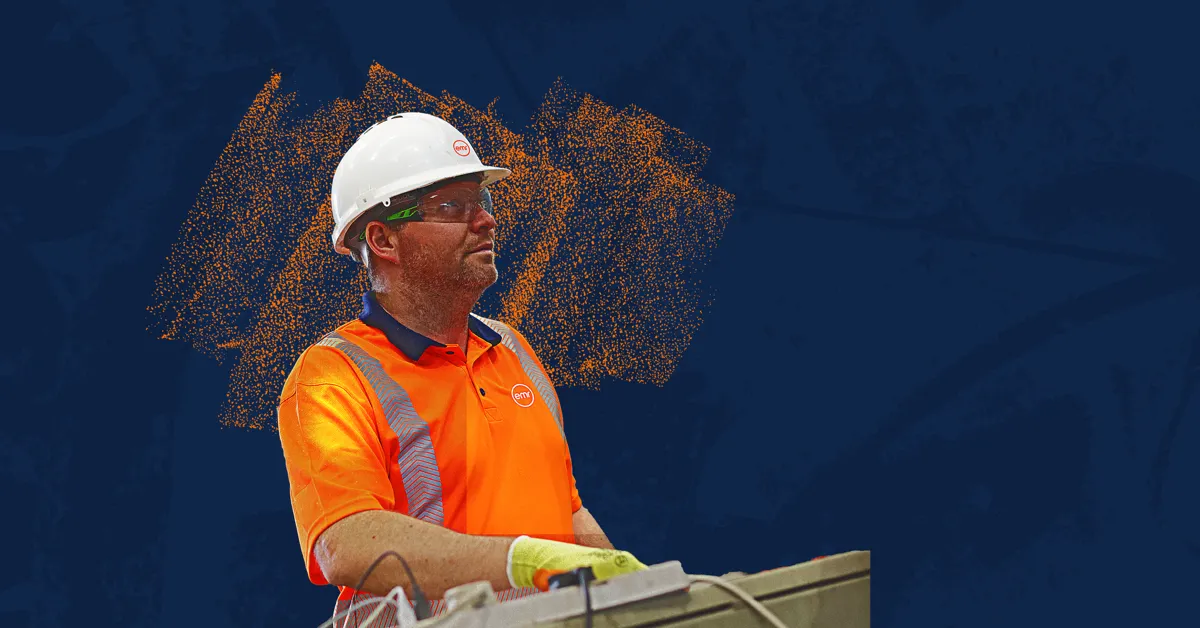 A person in a hard hat and safety vest operating a machine on a construction site.
